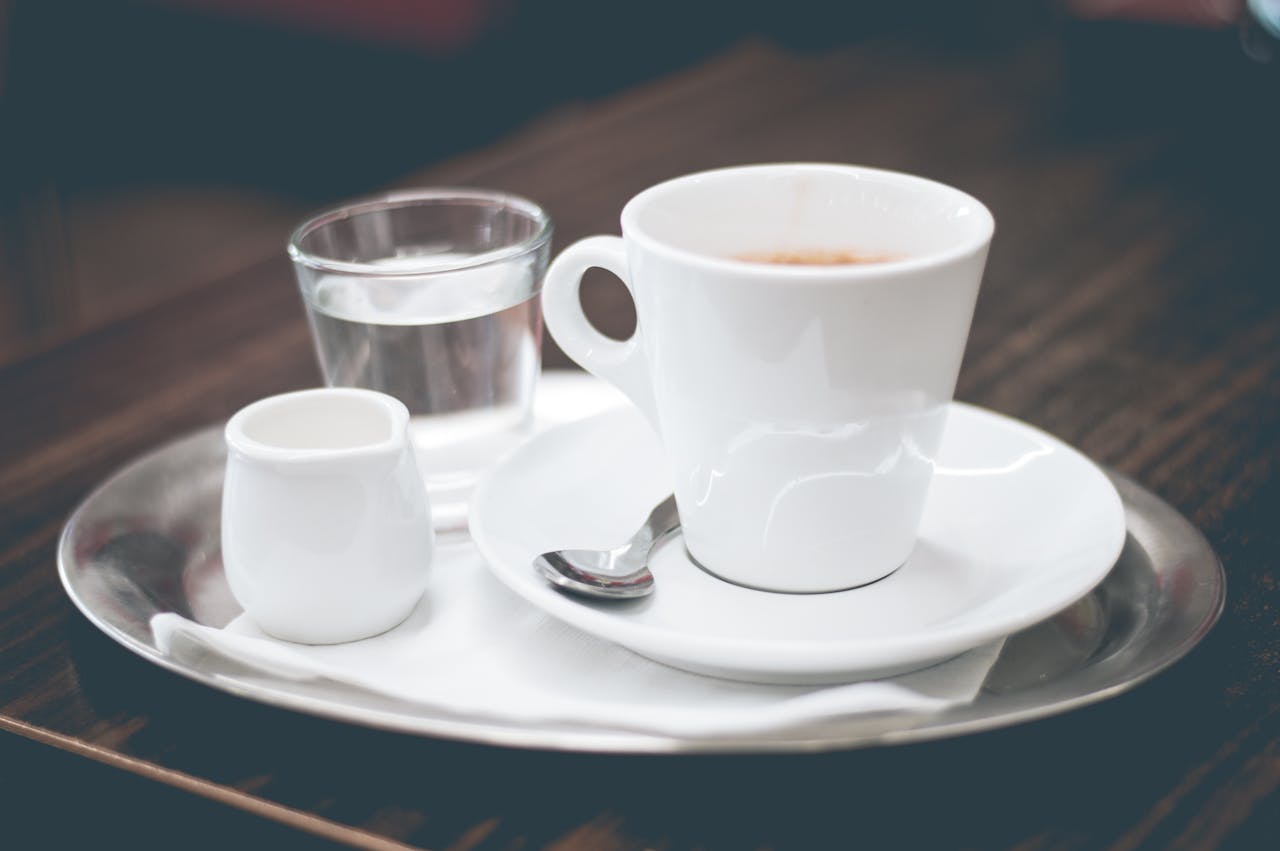 Sophisticated coffee presentation featuring espresso, water, and creamer on a metallic tray.