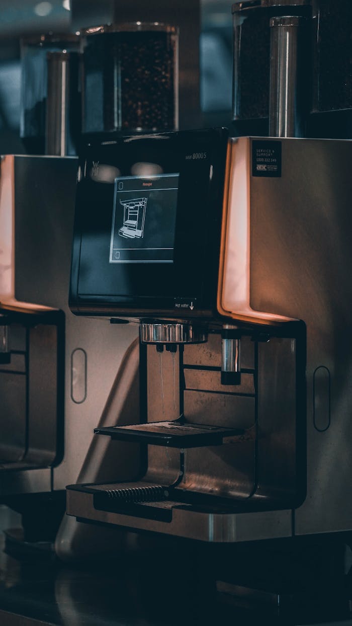 Close-up of a sleek coffee machine with touchscreen interface in a cafe setting.